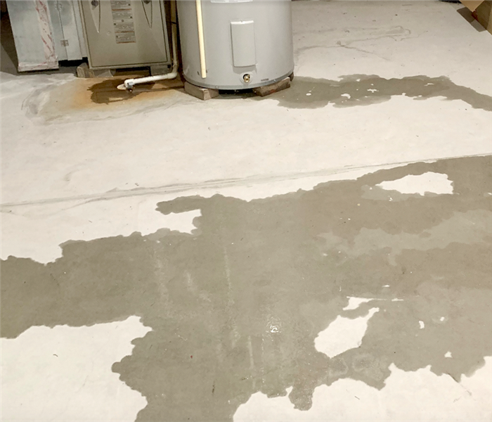 puddles of water leaking from a water heater in a basement